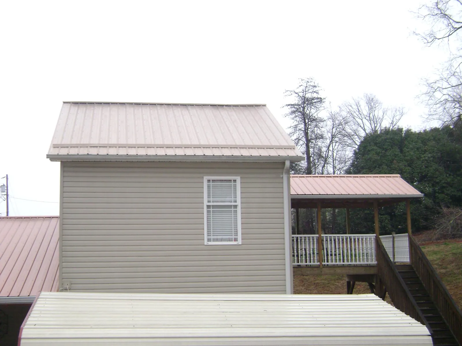 Tan metal roofs on a two story addition and attached porch, from a Roof Replacement job in Windsor